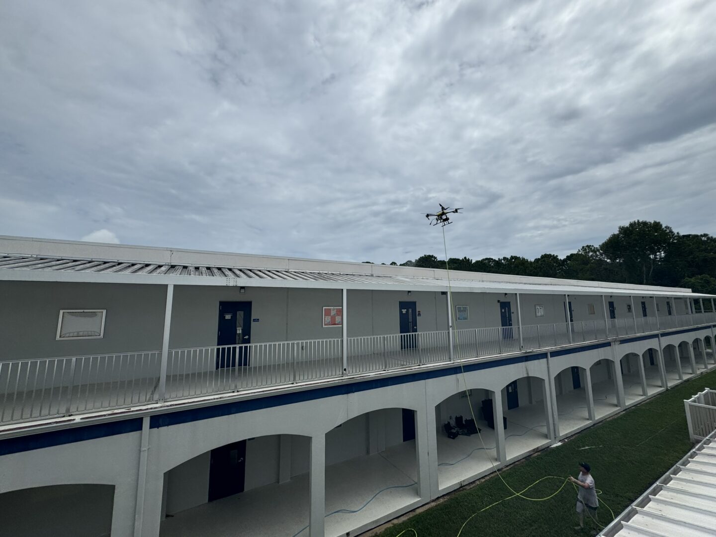 A drone-based soft-wash roof cleaning in progress on a commercial building